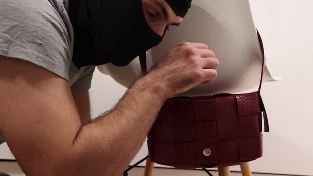 A masked individual discreetly pulls a wallet from a woman&rsquo;s bag in a staged theft scenario; close framing highlights the covert motion and emphasizes personal security awareness in everyday settings.