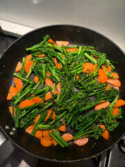 Stir fry of broccolini and carrot on the frying pan.