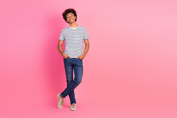 Young stylish man in casual clothing posing confidently against a vibrant pink background for...