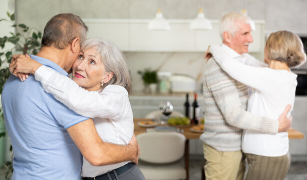 Elderly woman is dancing slow unhurried dance in hugs arms of her senior male partner. Senior men and women doing couple dancing during house party - Powered by Adobe