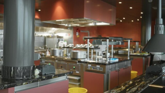 Industrial kitchen scene with defocused bokeh and soft stainless steel counters against warm red walls interior; backdrop copyspace backplate production.