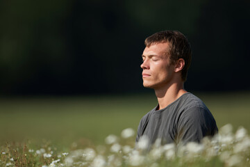 man sits peacefully with his eyes closed meditating in serene environment