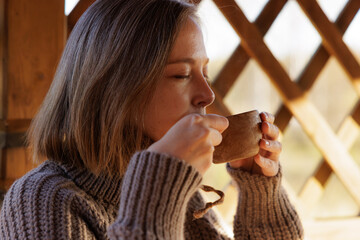 Enjoying a warm drink while relaxing in a cozy wooden cabin with a beautiful view outside