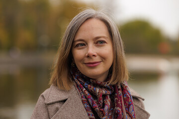 Warm autumn day by the lake with a woman in a stylish scarf enjoying the scenery