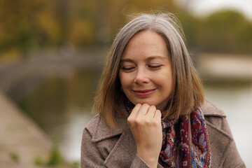 Contemplative woman enjoying a peaceful moment by the water in autumn