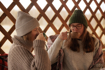 Warm cups and cozy hats brighten a chilly afternoon with friends in a wooden cabin