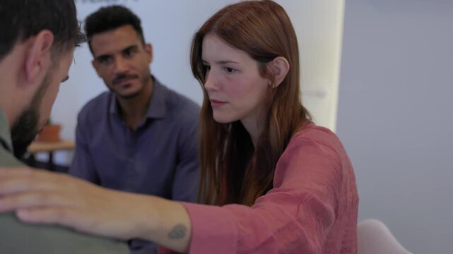 Young woman supporting a teammate during therapy group session. Members of a support group share empathy and encouragement in a safe space. Mental health and wellbeing concept. - Powered by Adobe