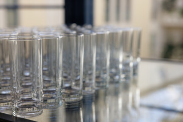 Rows of empty glasses wait for refreshing drinks on a sunny afternoon at a bustling outdoor venue