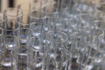 Rows of clear glasses ready to serve beverages for a festive gathering in a lively venue