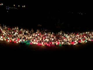 Hundreds of colorful cemetery candles glowing in the dark, forming a bright path of light in remembrance of the departed.