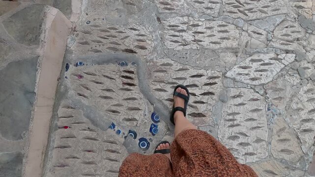 Woman feet with sandals walking on a path with Mataki evil eye blue orbs in Kas, Turkey