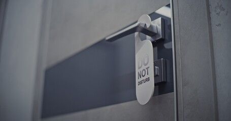 Close Up Sign Do Not Disturb and Door Hardware. Young Woman Enters Hotel Room and Gently Hangs Do Not Disturb Sign on Door Handle. Concept Privacy, Guest Comfort, Personal Time and Hotel Stay Routine.