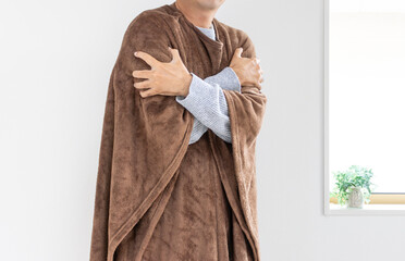 着る毛布を着て寒がる男性（30代、日本人、顔無し）