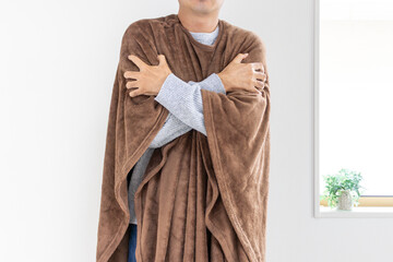 着る毛布を着て寒がる男性（30代、日本人、顔無し）