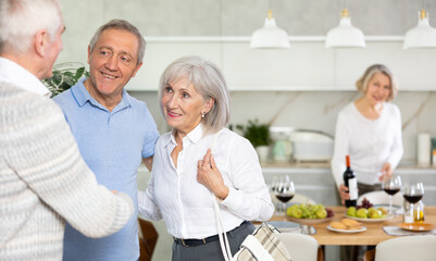Mature man happily shake hands with friends married pensioners couple, man and his wife arrived to visit home family event. Concept of communication, positive weekend with friends