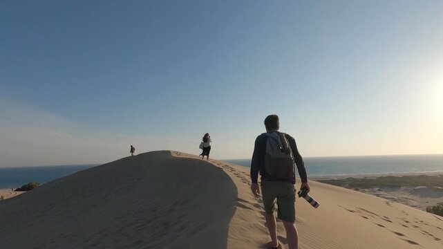 Group of young friends walking in Patara beach sand dunes with golden sand and sea on the background in Turkey, in slow motion