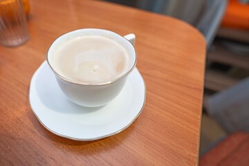 White porcelain cup with coffee and milk standing on a table during a meal