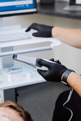 Dentist holding intraoral scanner near computer during digital dental exam