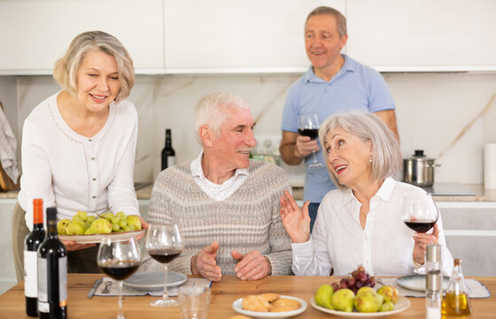 Couples of elderly women and men chatting and drinking wine at table.. - Powered by Adobe