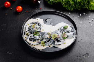 Black ravioli in creamy white sauce with microgreens, gourmet plating on dark slate