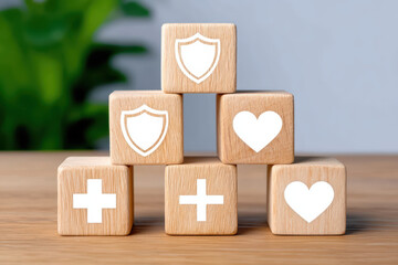 Obraz premium Wooden blocks stacked in pyramid shape with health, protection, and heart symbols, representing care, safety, and wellness concepts in calm setting