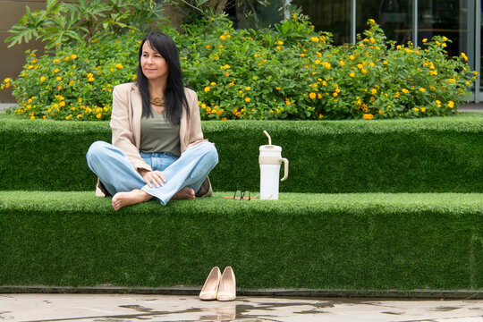 Mulher relaxando descal&ccedil;a em &aacute;rea verde urbana, descanso, pausa no trabalho, bem-estar, lifestyle, natureza, casual, equil&iacute;brio vida profissional e pessoal, sa&uacute;de mental, ver&atilde;o, tranquilidade