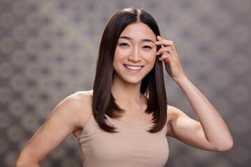 Naklejka premium Portrait of a proud female model showcasing glossy flawless skin and a gentle smile. Posing with graceful posture, glowing complexion and a minimal makeup look expressing self love.