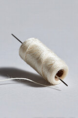 minimalist representation of thread and needle on clean ultrabright background evoking joy of creativity
