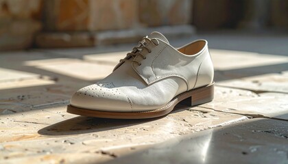 Naklejka premium Elegant white leather brogue dress shoe, exquisitely crafted with classic detailing, resting on a sunlit textured stone floor, highlighting timeless fashion and refined style