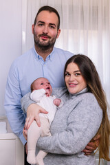 Young parents happily holding newborn baby at home