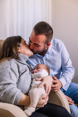 Happy parents kissing holding their newborn baby