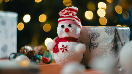 Christmas puppet on a table in front of the tree and presents