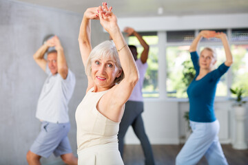 Active senior lady enjoying passionate flamenco dance during group class with adult men and women....