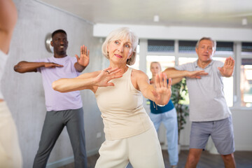 Group of multinational sports aged people rehearsing modern dance in dance hall