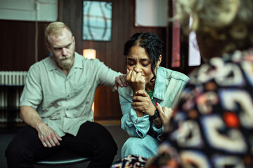 Adult woman crying in support group as peers comfort her