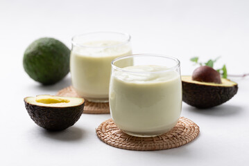 Avocado smoothie with milk in glass and avocado fruit on white background, Healthy drink