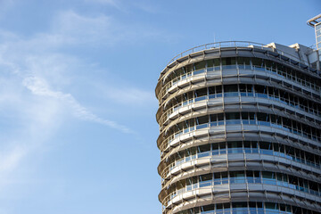 Modern architectural building with curved glass facade and metal accents, showcasing contemporary design against a clear blue sky, representing urban development and innovation