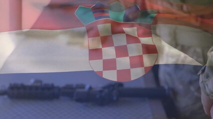 Soldier reaching for magazine, inspecting and preparing rifle while flag overlay waving over scene - Powered by Adobe