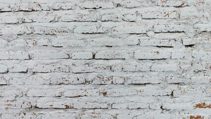 A textured white brick wall with natural cracks and weathered details, perfect as a background or design element. This photo is ideal for graphic design, advertising, websites, and product mockups.