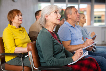 Older male and female students listening to lecture in university