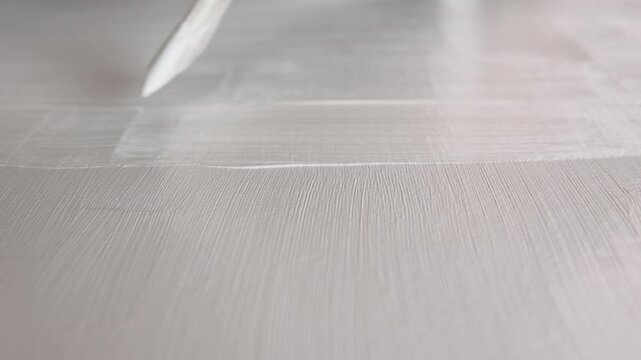 Close up of an artist priming canvas with white ground, preparation for painting. Selective focus