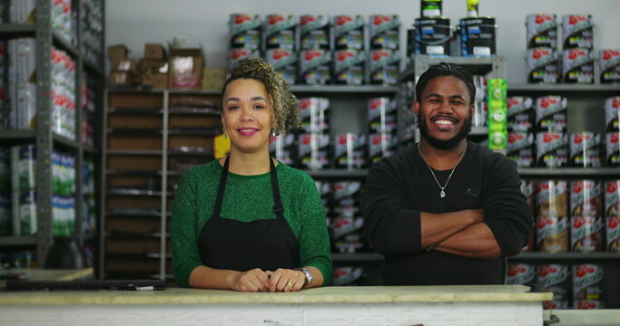 Smiling employees standing together behind the counter in a hardware store, showcasing a professional and friendly work environment - Powered by Adobe