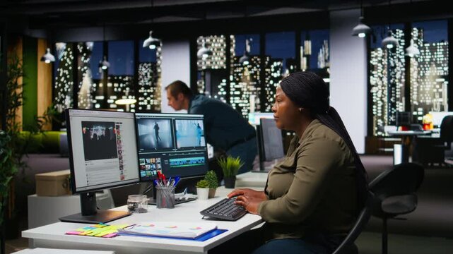 Female expert editor working in video production industry at agency office, doing color grading and creating a montage on dual monitors. Creative process with multimedia tech tools. Camera A.