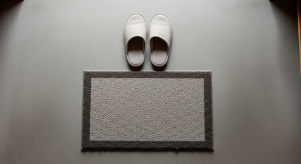 Top‑down still life of plain slippers and mat at a genkan
