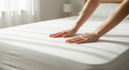 Hands spreading plain sheets in a bright bedroom, new‑life clean feel
