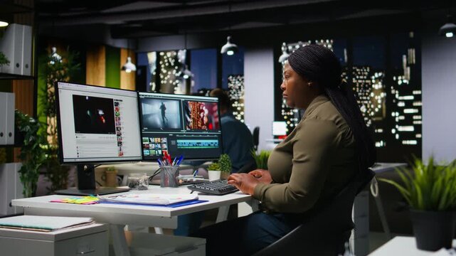 Woman film editor yawning and stretching her back on chair at night, feeling overburdened and weary to finish video editing project in time. Videographer working under pressure, fatigued. Camera A.