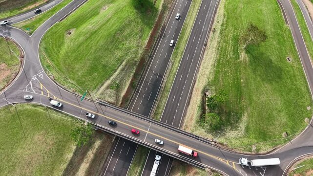 Aerial view of a highway interchange with vehicles and green grassy surroundings