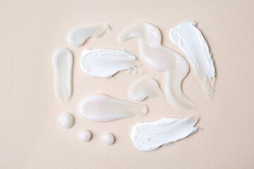 Samples of moisturizing creams on beige background, flat lay