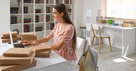 Happy female student with laptop and books studying in library