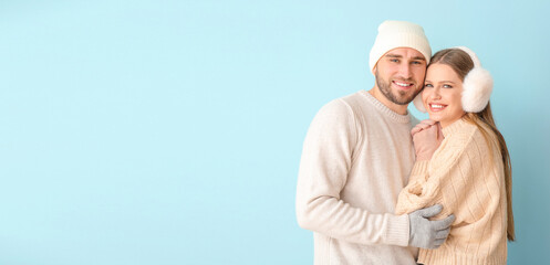 Portrait of happy couple in winter clothes on color background